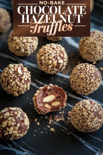 Close-up of no-bake chocolate hazelnut truffles arranged on a dark marble surface. Each truffle is coated in finely chopped hazelnuts, with one cut open to reveal a rich chocolate ganache filling and whole hazelnuts inside. The text overlay reads "No-Bake Chocolate Hazelnut Truffles" in bold lettering.