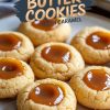 A plate of peanut butter cookies filled with caramel. The cookies have a soft, golden-brown exterior with smooth, glossy caramel in the center. The arrangement emphasizes the homemade and delicious appeal.