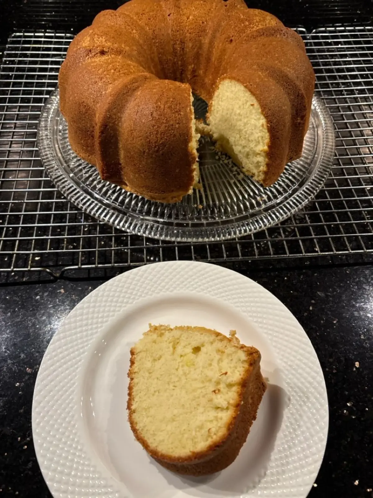 Golden brown pound cake baked by AJ, shown whole on a wire rack and also plated in a slice on a white dish. The texture looks moist with a fine crumb.
