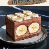 plated slice of chocolate banana mousse cake showcasing its distinct layers: a chocolate sponge base, creamy chocolate mousse enveloping whole bananas, and a topping of banana slices. The slice is presented on a light plate with a speckled glaze.