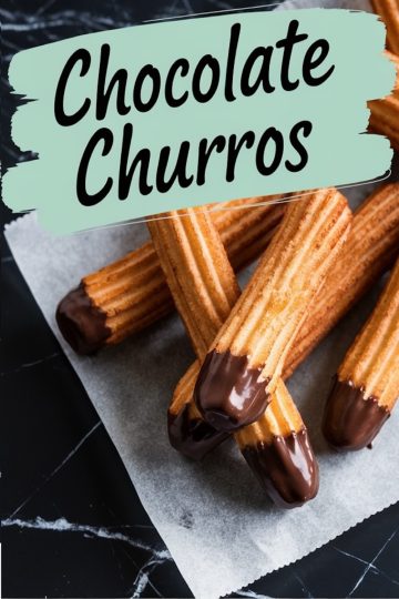 Close-up of chocolate-dipped churros arranged on parchment paper over a dark marble surface. The churros have a golden-brown crispy texture with glossy chocolate coating the ends. A text overlay reads "Chocolate Churros" in bold lettering on a mint green background.