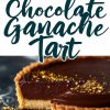 A chocolate ganache tart with a slice removed, revealing its velvety filling and crumbly crust. The tart is garnished with a light dusting of gold sprinkles, resting on a dark textured surface with a raspberry for accent.