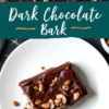 A close-up of dark chocolate bark topped with chopped nuts, placed on a white plate. The glossy chocolate surface contrasts with the crunchy nut topping. A text overlay reads “Dark Chocolate Bark.”
