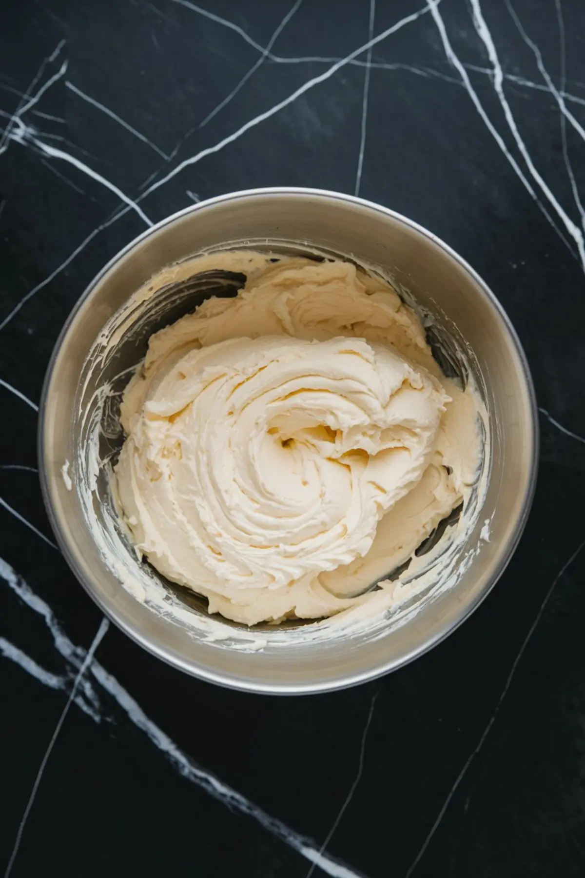 A mixing bowl filled with thick, creamy whipped filling, likely the base for the Easter dip. The bowl is set on a black marble countertop.