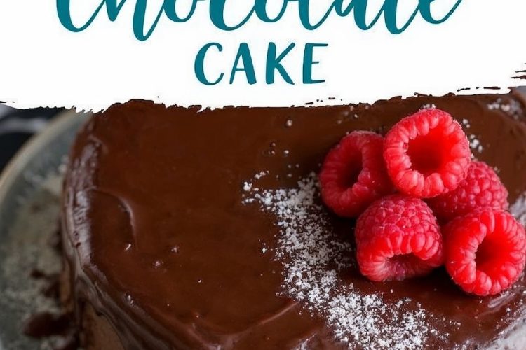Flourless chocolate cake covered in a smooth chocolate ganache, decorated with powdered sugar and a cluster of fresh raspberries on top, displayed on a ceramic plate with a dark marble background.