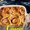 Banana cinnamon rolls baked in a white dish, swirled and golden with glossy caramelized banana glaze, set against a black marble backdrop with yellow text overlay.