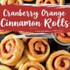 Freshly baked cranberry orange cinnamon rolls arranged on a dark surface, drizzled with a rich orange glaze. A red banner with “Cranberry Orange Cinnamon Rolls” overlays the image.