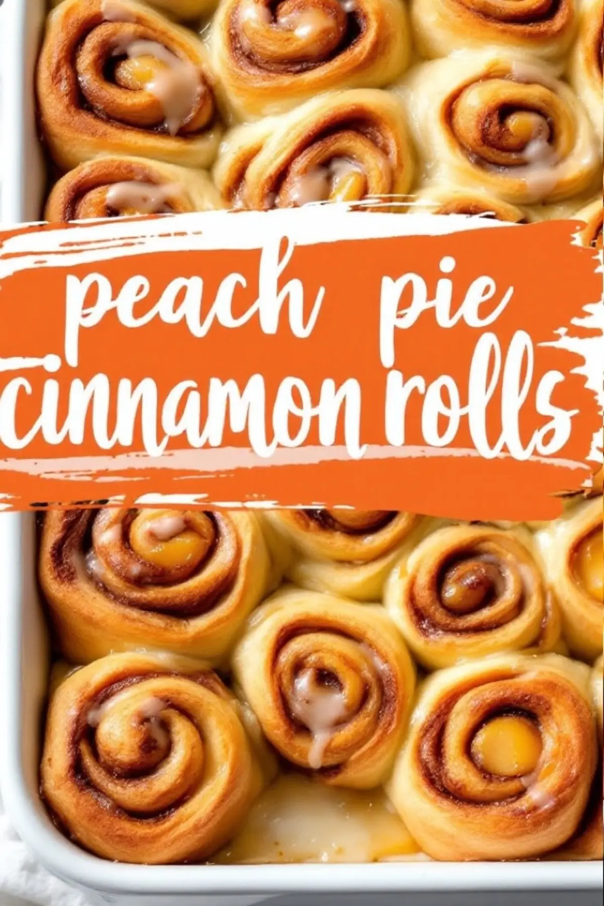 Freshly baked peach cinnamon rolls in a white rectangular baking pan, filled with cinnamon swirl and diced peaches, lightly topped with icing.