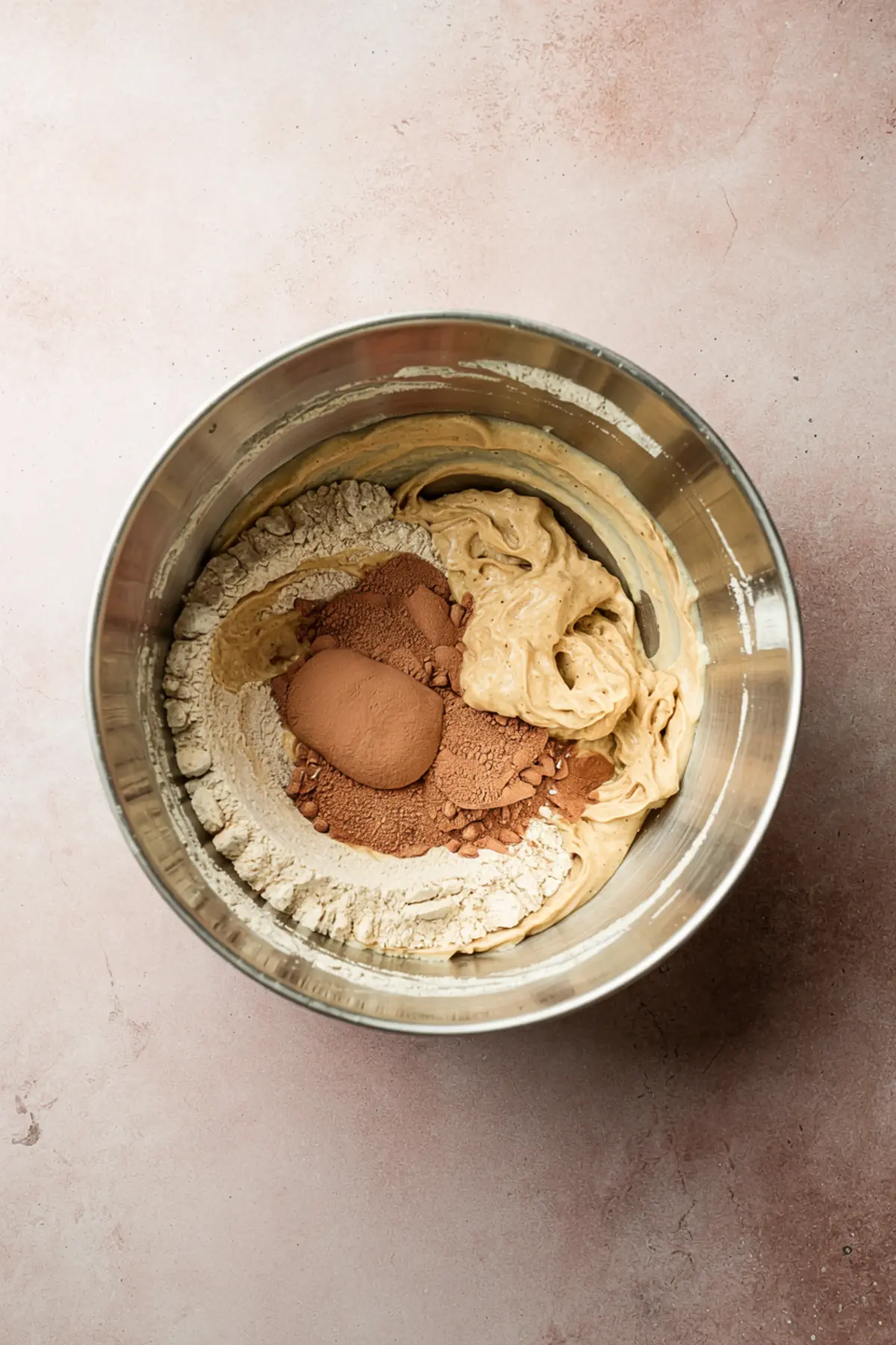 Mixing bowl with sourdough starter, cocoa powder, and flour partially combined, showing the process of preparing chocolate sourdough dough.