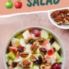Top view of an apple salad featuring green and red apple chunks, red grapes, celery pieces, dried cranberries, and pecans, all coated in a creamy dressing and served in a speckled bowl with text overlay that reads “Easy Apple Salad.”