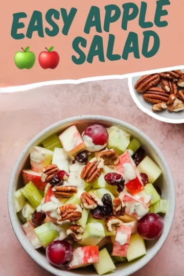 Top view of an apple salad featuring green and red apple chunks, red grapes, celery pieces, dried cranberries, and pecans, all coated in a creamy dressing and served in a speckled bowl with text overlay that reads “Easy Apple Salad.”