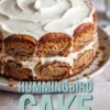 Frosted hummingbird cake decorated with cream cheese icing and toasted edges, displayed above a close-up slice showing layered banana-pineapple cake filled with pecans and fluffy cream cheese frosting.