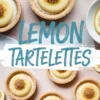 Flat lay of lemon tartelettes with smooth lemon curd and crisp tart shells, garnished with brown sugar clusters, surrounded by lemon slices on a blush pink backdrop with “LEMON TARTELETTES” title.