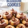 Chocolate-dipped peanut butter blossom cookies with Hershey’s kisses and sea salt served with a glass of milk, styled for a cozy dessert moment.
