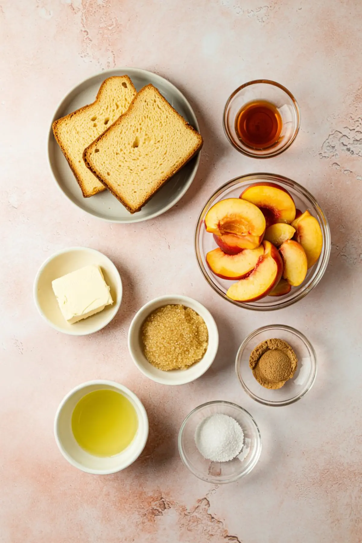 Flat lay of ingredients for peach pound cake including sliced peaches, pound cake slices, butter, brown sugar, white sugar, cinnamon, oil, and vanilla extract, arranged on a pink surface. This setup emphasizes baking inspiration and fresh seasonal ingredients.