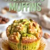 Golden pistachio muffins cooling on a wire rack, topped with chopped pistachios and peanuts, with soft green interiors and rustic paper liners on a light kitchen surface.