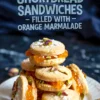 A stack of pistachio shortbread sandwich cookies filled with orange marmalade, topped with crushed pistachios and powdered sugar, arranged on a white plate with a dark moody background and bold text overlay.