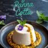 Vegan panna cotta with silky texture, served on a dark plate with passion fruit pulp drizzled over and around, topped with mint and an edible flower, styled on a black marble background.