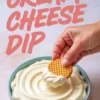 Pink and teal bowl of silky cream cheese dip with text overlay “CREAM CHEESE DIP,” and a hand holding a round waffle cookie dipped into the creamy mixture, highlighting a simple dessert option.
