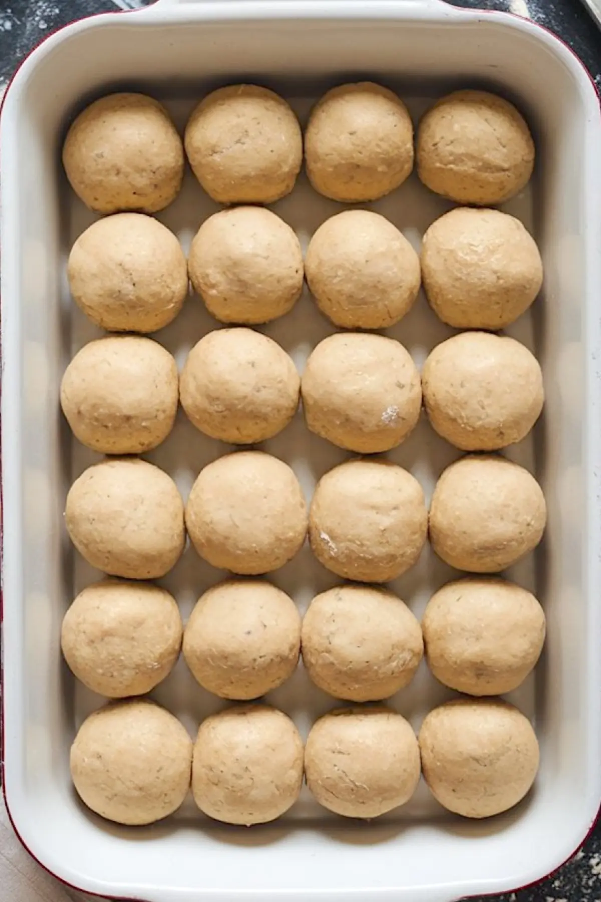 Overhead view of a baking dish filled with evenly spaced dough balls, prepped for baking King’s Hawaiian cheesecake danish rolls.