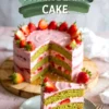 Sliced matcha strawberry layer cake with vibrant green sponge and pink strawberry frosting, garnished with fresh strawberries. A single slice is served on a plate with a gold fork, showcasing the soft layers and berry filling.