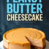Whole peanut butter cheesecake with smooth caramel-like glaze on top and one slice removed, showcasing creamy interior layers and graham cracker crust, displayed on a marble cake stand.