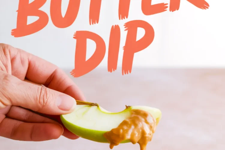 Hand holding a green apple slice dipped into creamy peanut butter dip, with a bowl of smooth peanut butter spread below and bold orange text reading “Peanut Butter Dip.”