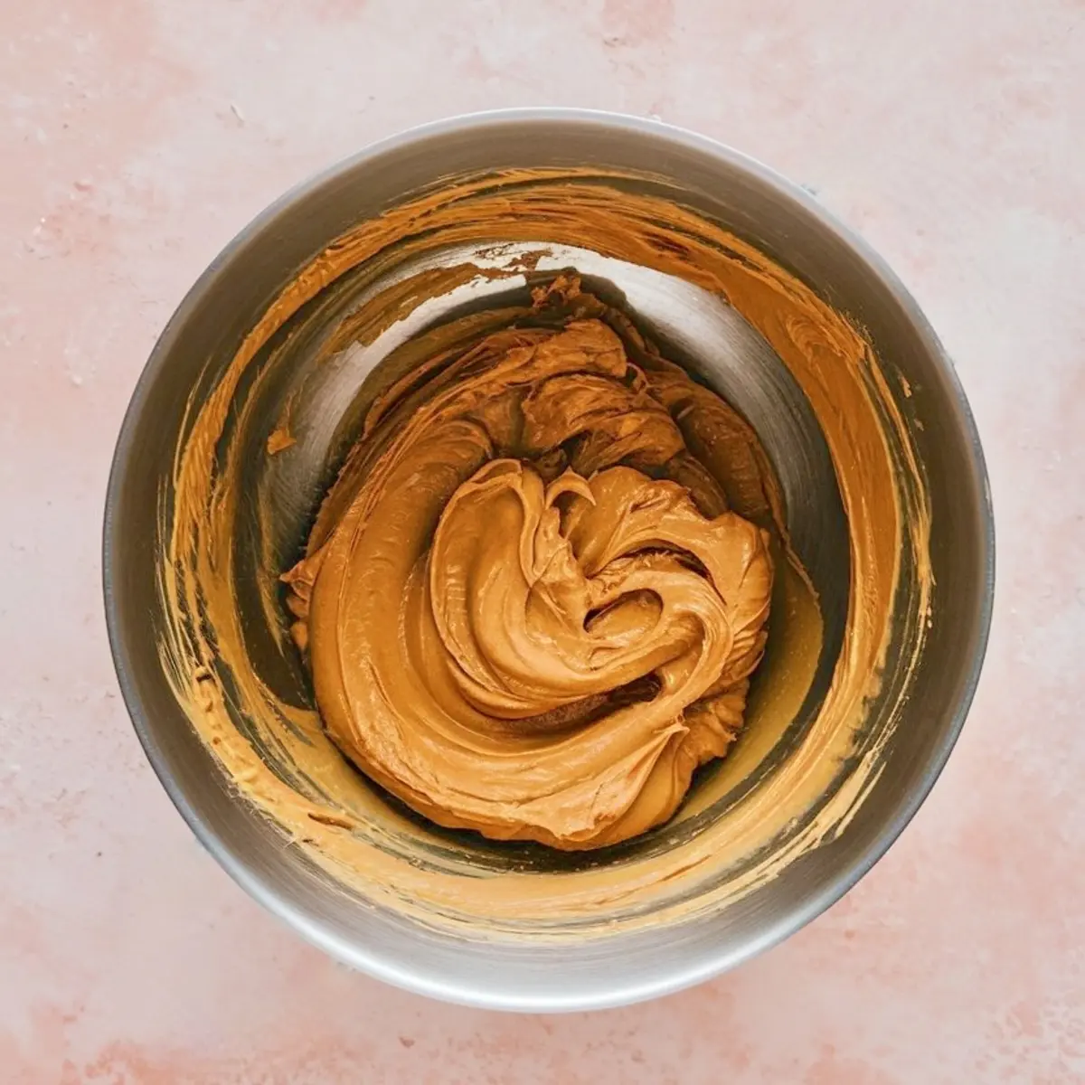 Creamy peanut butter mixture swirled smoothly in a stainless steel mixing bowl, showing rich texture ideal for dessert dips, spreads, or peanut butter recipes.