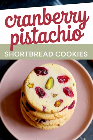 Top-down view of a stack of round cranberry pistachio shortbread cookies on a pink ceramic plate with visible chunks of cranberries and pistachios; includes recipe title in bold font.
