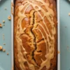 Peanut butter banana bread with caramel glaze drizzle in white loaf pan on mint green plate - finished healthy banana bread recipe