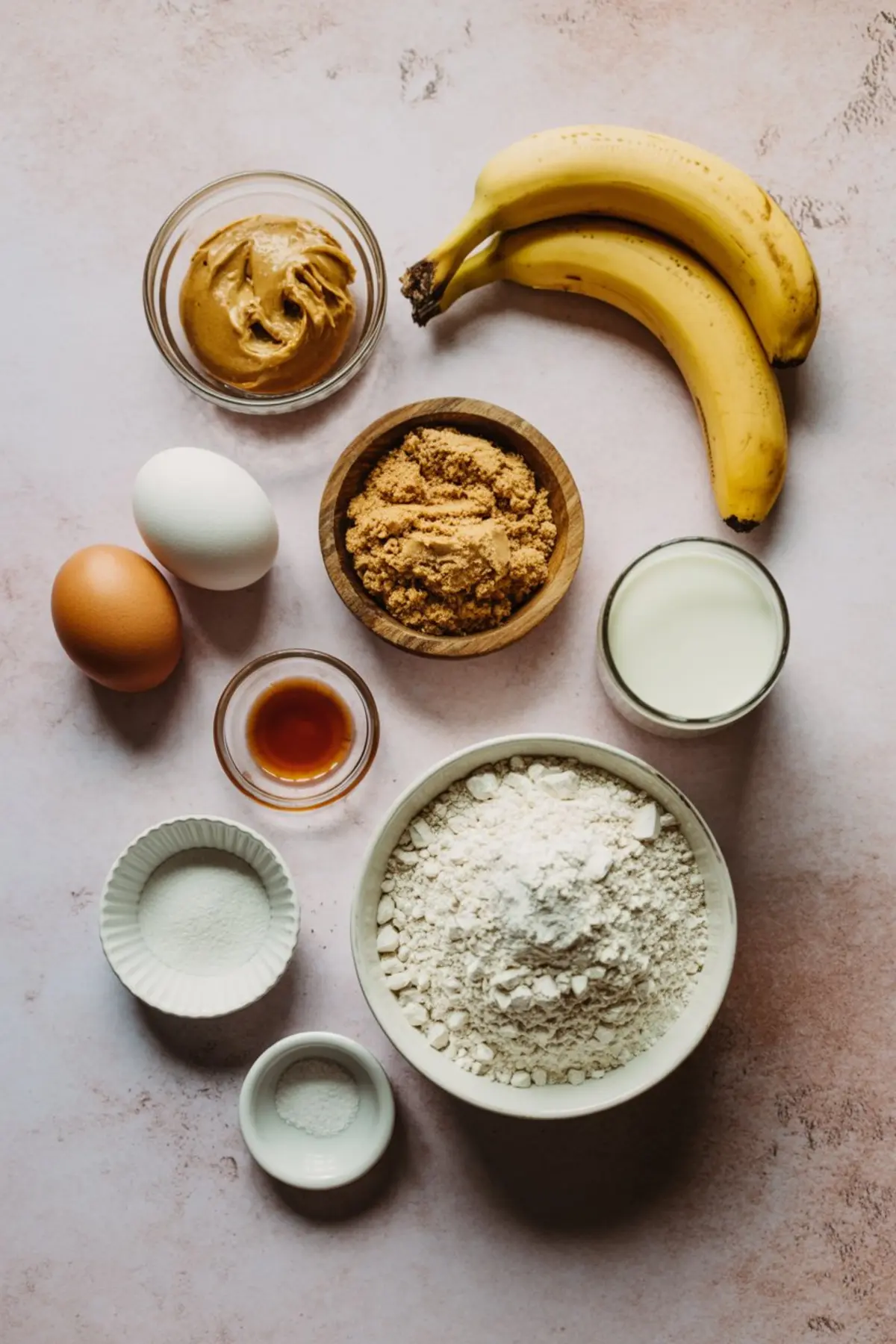 Peanut butter banana bread recipe ingredients laid out: bananas, eggs, peanut butter, flour, milk, brown sugar - ripe banana recipes preparation