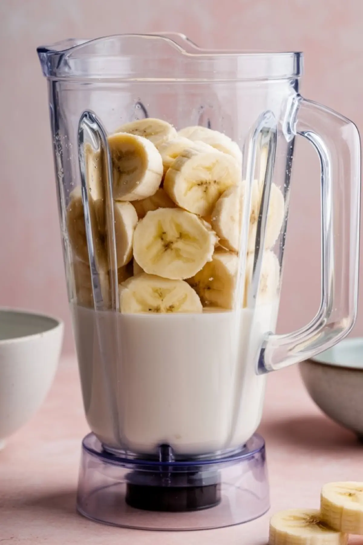 A blender filled with sliced bananas and milk, ready to be blended into a creamy smoothie.