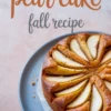 Round baked pear cake topped with sliced pears arranged in a circular pattern on a blue plate with text overlay reading “pear cake fall recipe.”