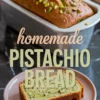 Finished loaf of golden-brown pistachio bread in a baking pan topped with chopped pistachios, with a sliced piece on a pink plate showing green nut-speckled crumb.