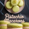 Collage image featuring a top view of green pistachio macarons with crushed nuts on top, and a close-up of one macaron with pink filling, styled with “Pistachio Macarons” text in light pink on a dark background.