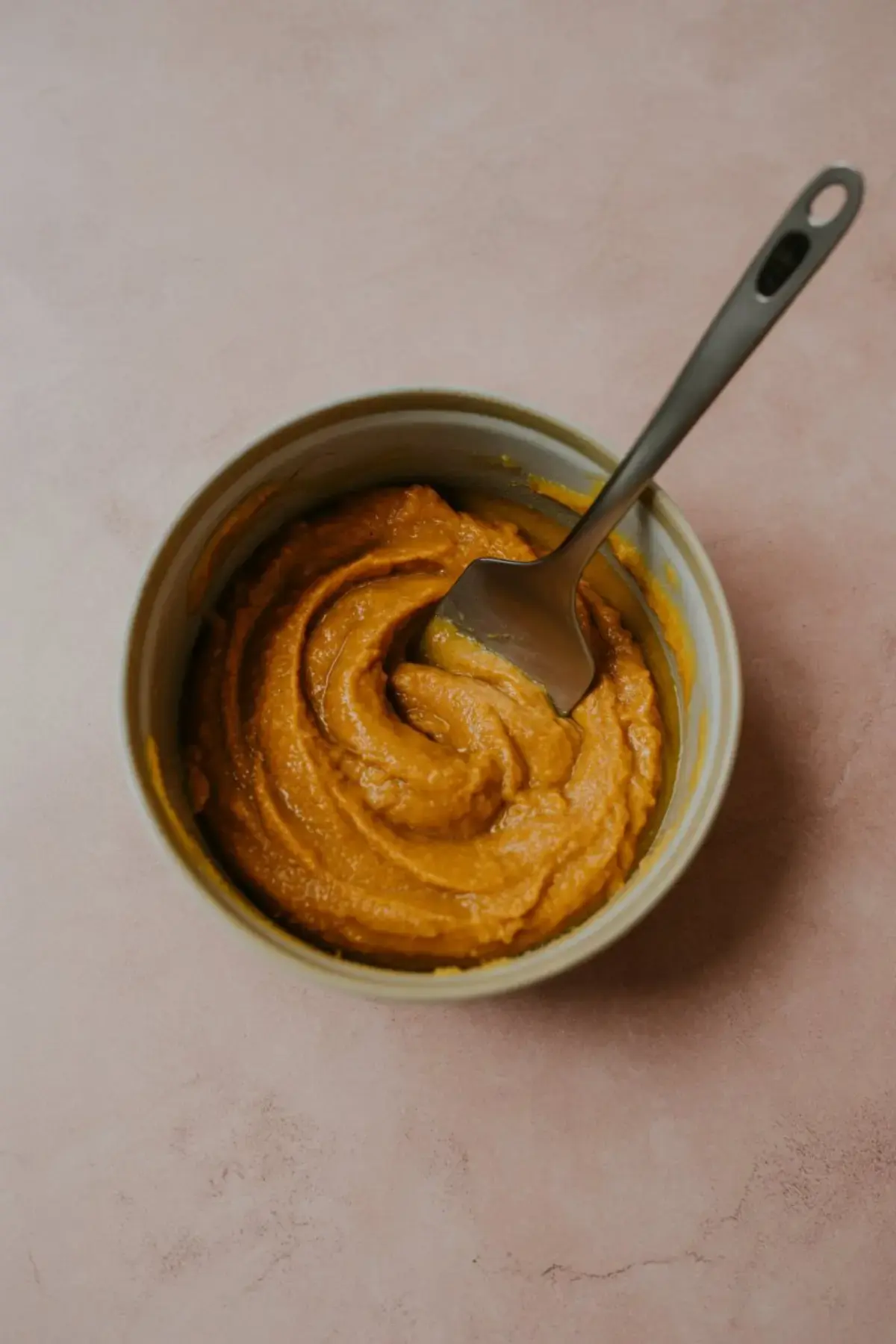 A bowl of smooth, fully blended pumpkin fluff mixture with a spatula resting inside, showcasing the creamy consistency of the dessert dip.