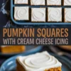 Tray of pumpkin squares topped with white cream cheese icing with a slice served on a blue plate in front.