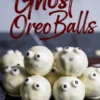 Close-up of stacked ghost-themed Oreo balls with candy eyes and white chocolate coating, placed on a dark reflective surface with Halloween dessert text overlay.