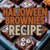 Decorated Halloween brownies topped with candy eyes and colorful orange and purple icing, arranged neatly on a blue tray with text overlay reading “Halloween Brownies Recipe.”