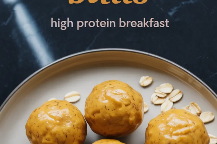 Plate of glossy pumpkin protein balls with one sliced open to reveal a moist, dense texture, surrounded by scattered oats on a black marble background, with text overlay promoting high protein breakfast.