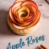 Overhead shot of an apple rose pastry with delicately layered red apple slices on a puff pastry base, styled with cinnamon sticks and the text “Apple Roses” in blue cursive font on a marble-textured surface.