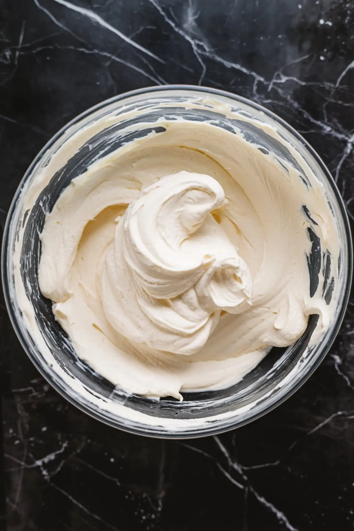 Thick whipped cream cheese filling with smooth, fluffy texture in a mixing bowl, ready for cheesecake assembly.