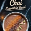 Overhead view of a chocolate chai smoothie bowl garnished with cacao nibs, ground cinnamon, and whole cardamom pods, set against a dark marble background with overlay text reading “Chocolate Chai Smoothie Bowl.”