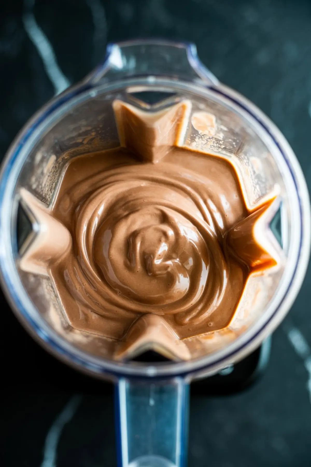 Creamy chocolate smoothie blended in a high-speed blender, with smooth texture and glossy finish.