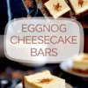 Close-up of a thick eggnog cheesecake bar on a dessert plate, showing a creamy eggnog filling with a cinnamon-dusted top and spiced cookie crust on a dark table.
