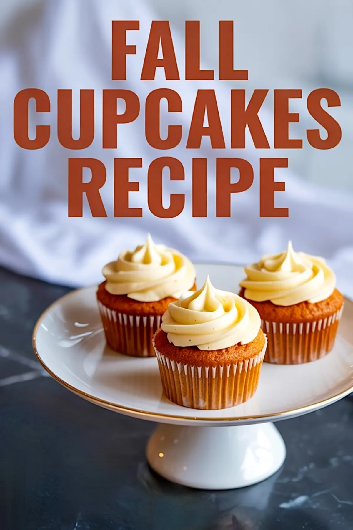 A vertical collage of three pumpkin cupcakes topped with vanilla frosting on a white cake stand, placed on a dark marble surface with “Fall Cupcakes Recipe” text overlay in bold orange letters.