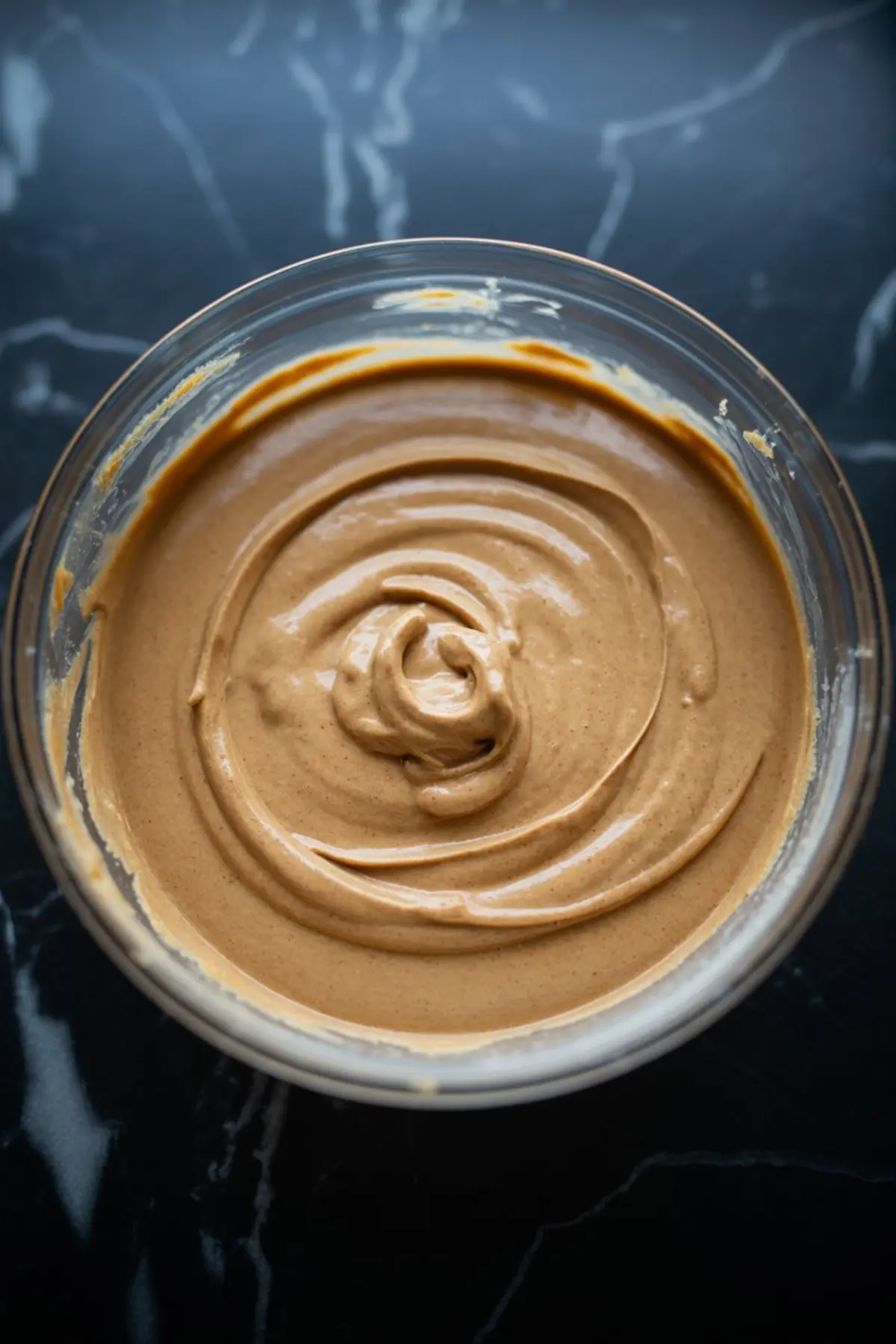 Smooth and creamy gingerbread cheesecake batter swirled in a glass bowl, ready for baking.