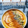 Pumpkin pie smoothie bowl with a swirl of maple syrup, a line of ground cinnamon, pumpkin seeds, chia seeds, and granola, with recipe title text overlaid at the top.