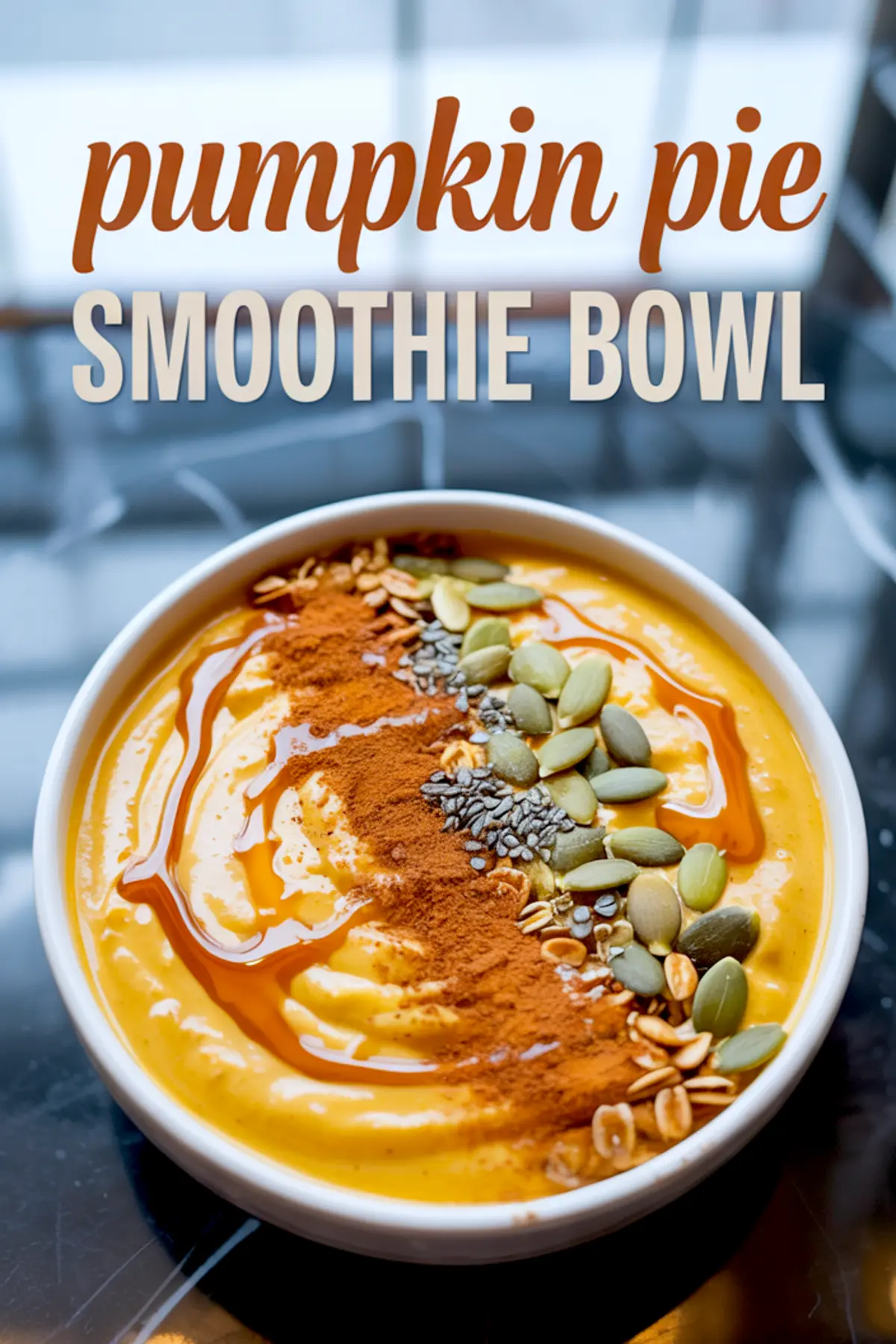 Pumpkin pie smoothie bowl with a swirl of maple syrup, a line of ground cinnamon, pumpkin seeds, chia seeds, and granola, with recipe title text overlaid at the top.