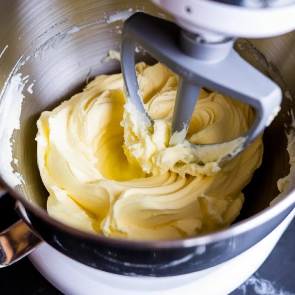 Whipped butter creamed in a stand mixer with a paddle attachment inside a stainless steel mixing bowl.